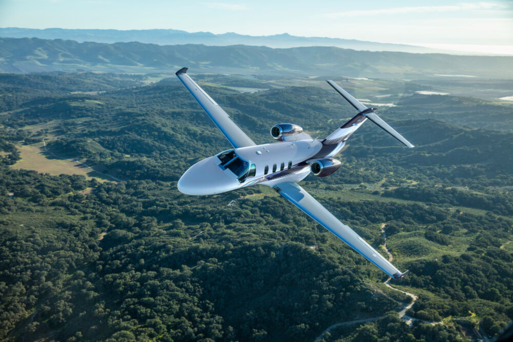 Super light Cessna Citation Flying over Moutains trees and ocean