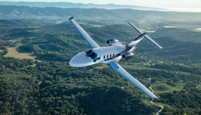 Super light Cessna Citation Flying over Moutains trees and ocean