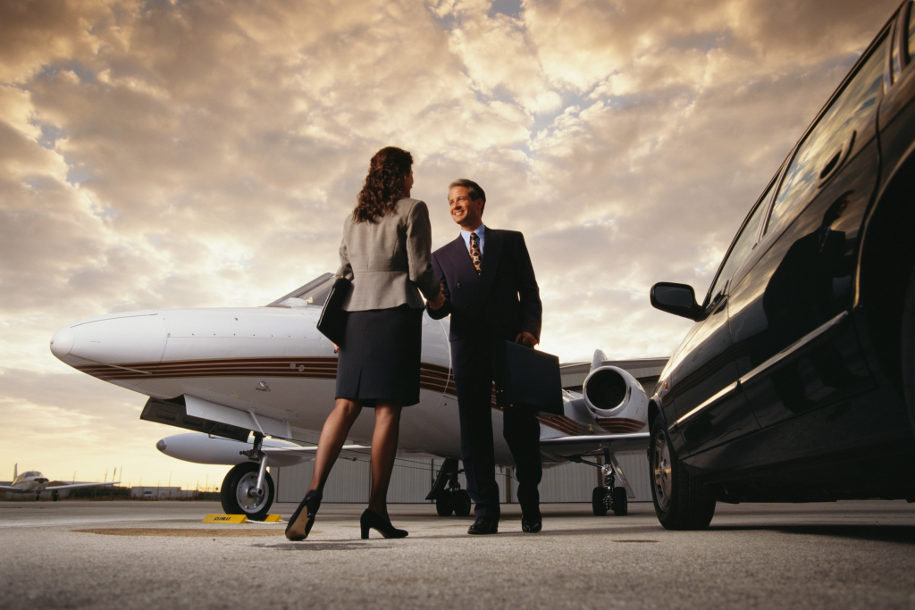 business people shaking hands in front of private jet