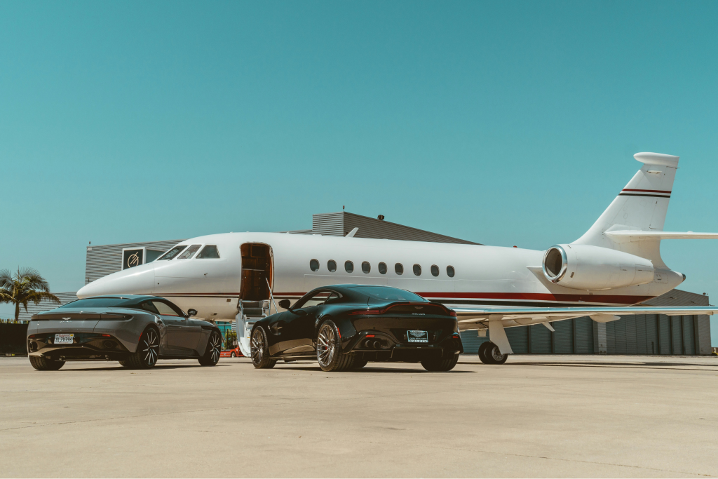 private jet and two astin martins on an airport tarmac