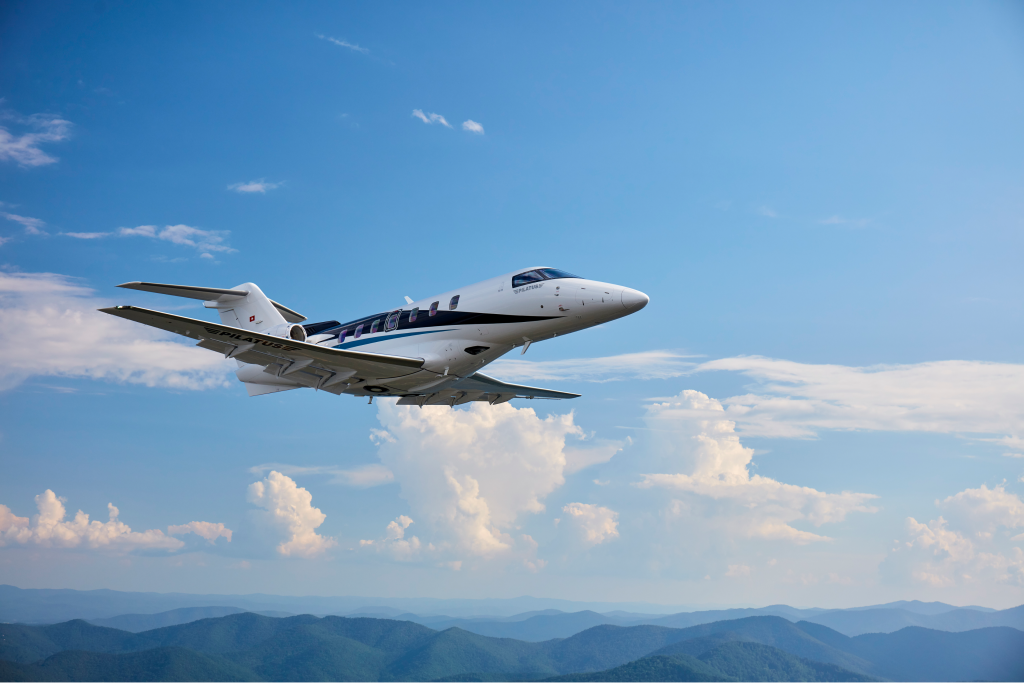 PC-24 private jet flying above the pink and white clouds